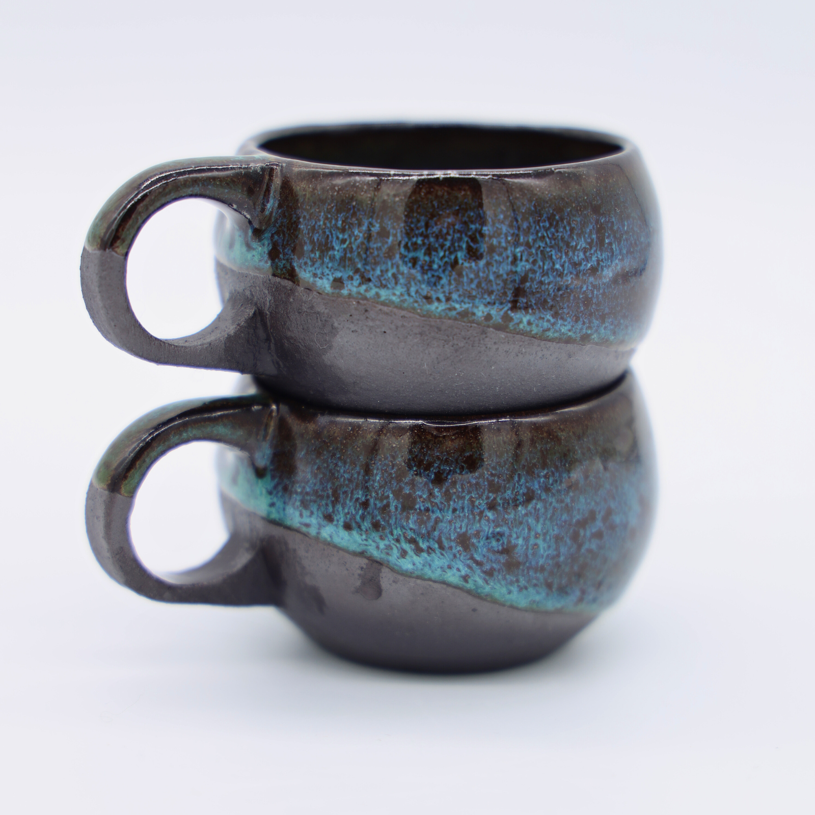 Tasses avec anse en grès noir avec émail vert fabriquées artisanalement à Paris